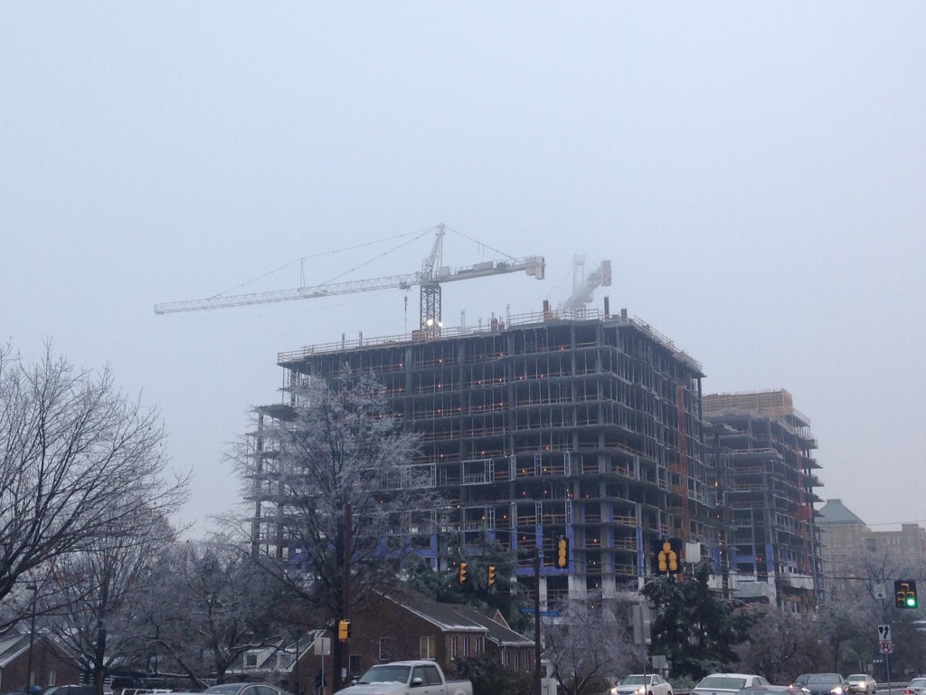 thickening fog obscuring cranes atop new construction building