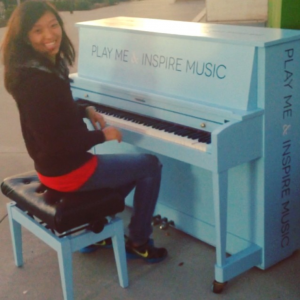 girl at outdoor piano smiling with gleeful expression of joy