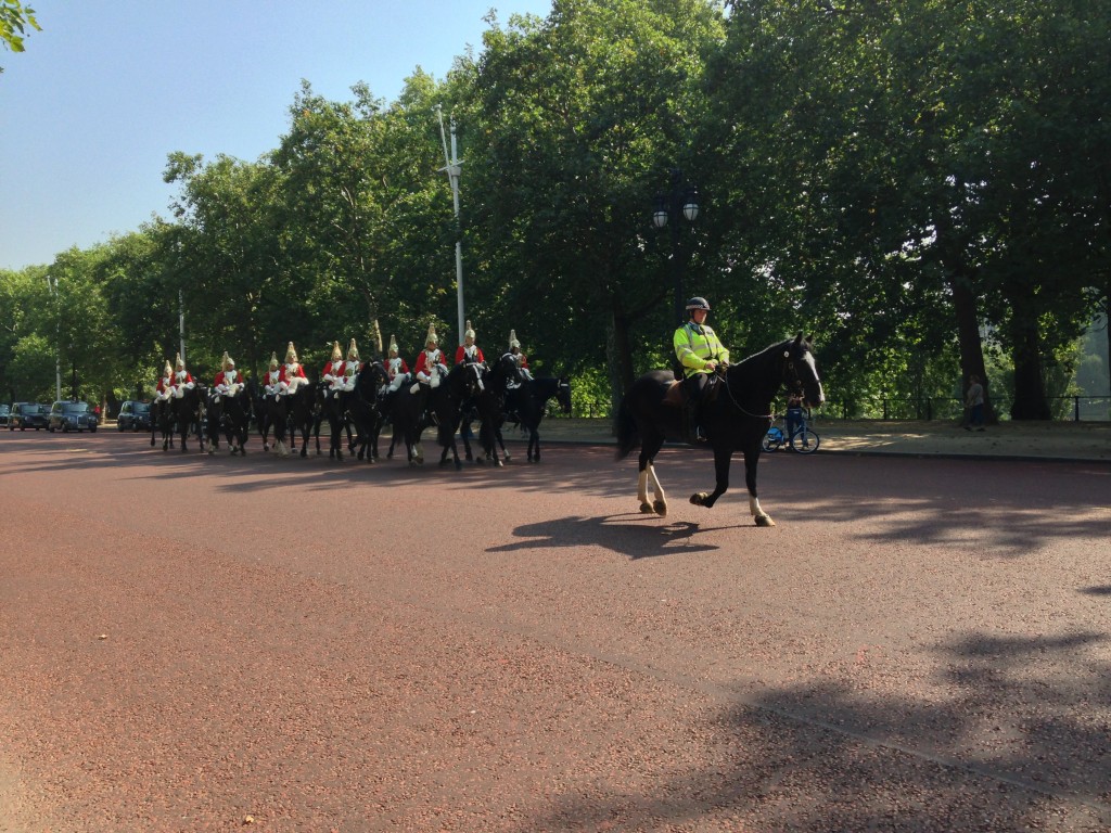 guards on horseback riding towards buckingham palace