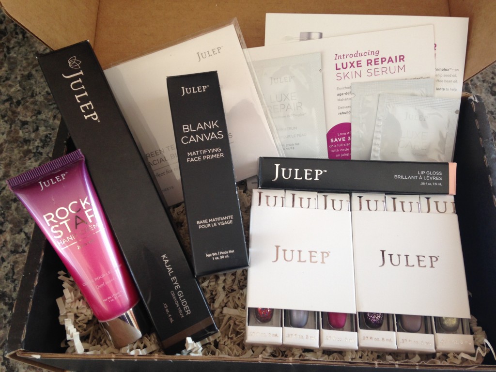 julep naughty and nice mystery box contents including rock star hand creme, kajal eye glider, blank canvas primer, green tea blotting papers, luxe repair samples, luxe care samples, lip gloss, and polishes in america, joanna, nellie, aviva, alaina, and brenda
