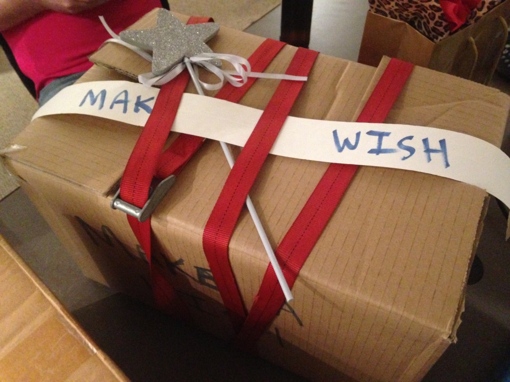 cardboard box with star wand, make a wish sign, and red belt wrapped together