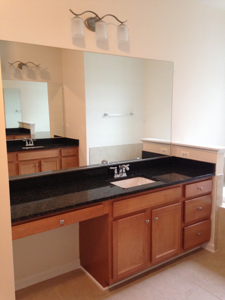 master bathroom sink with vanity area, dark granite countertops, and light wooden drawers