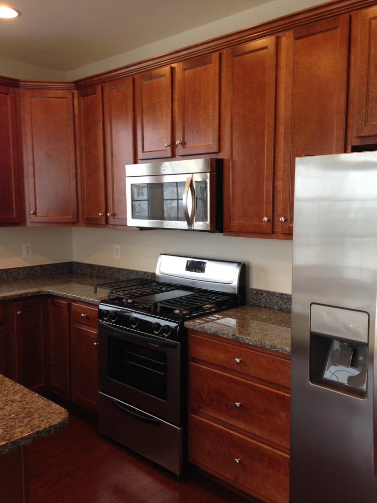new kitchen in condo with stainless steel appliances, wood cabinets, and granite countertops