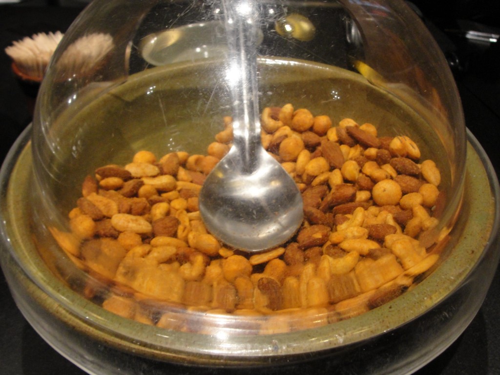seasoned nuts covered by plastic dome with metal spoon