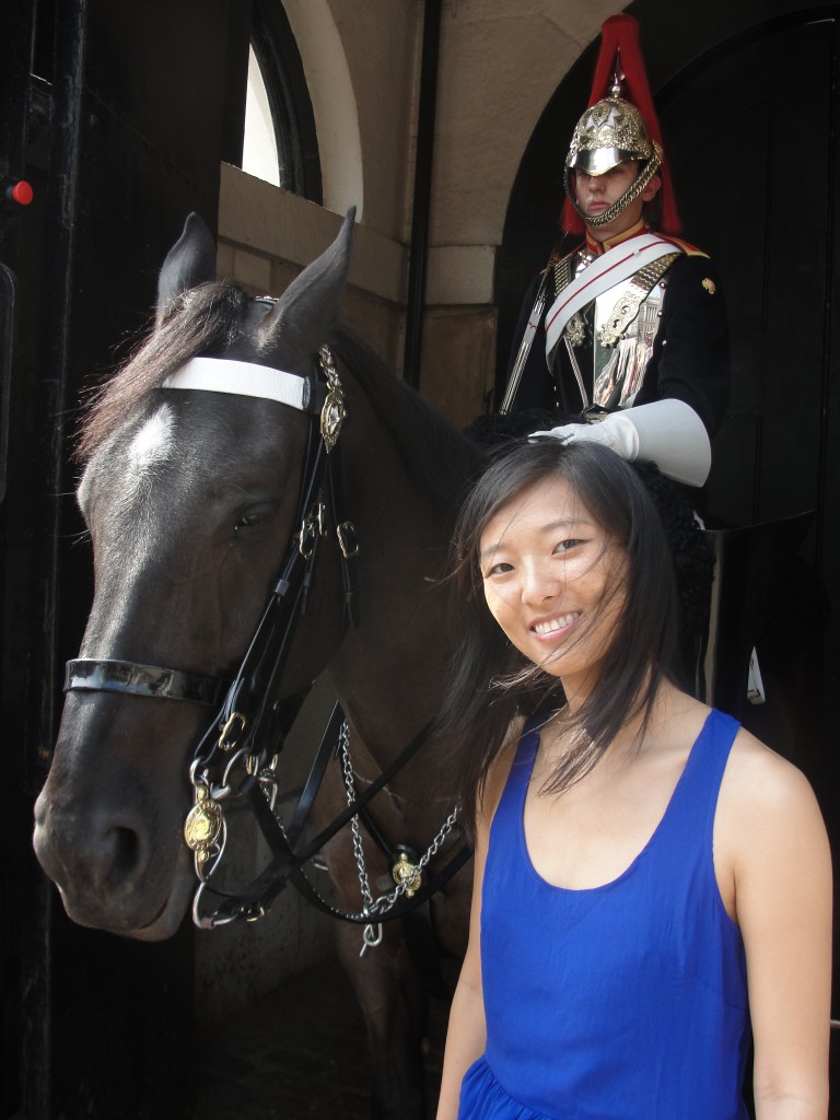 girl standing next to horse with guard sitting on it
