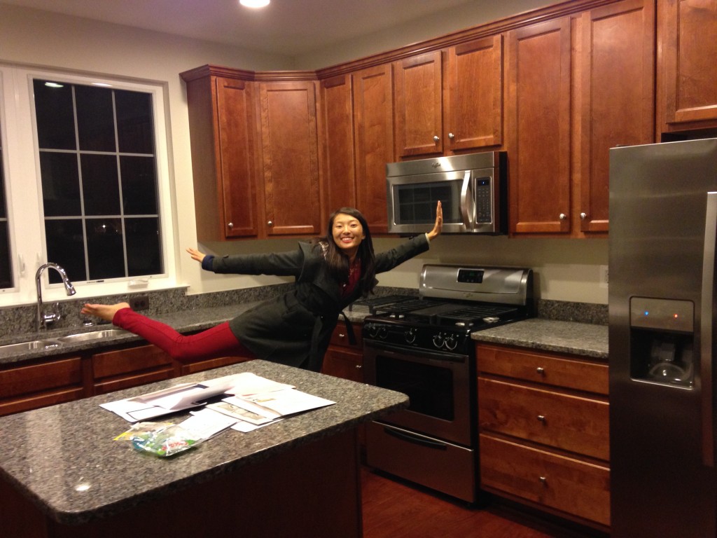 happy girl prancing in kitchen of brand new condo balancing on one leg with arms and other leg outstretched