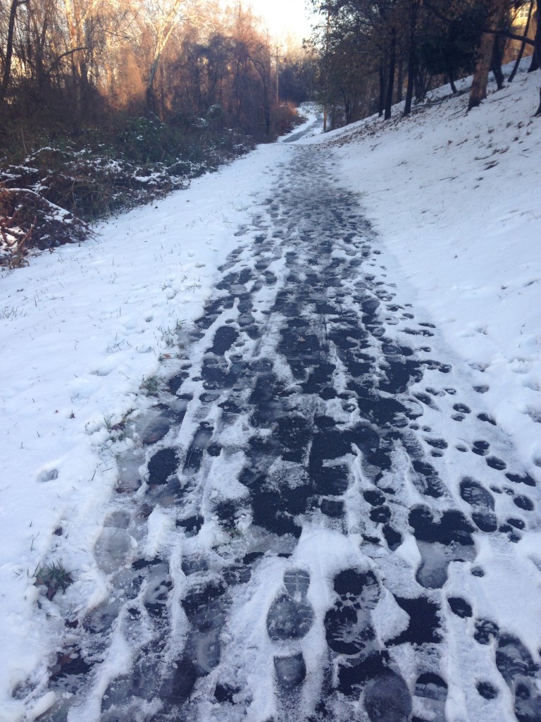 running trail covered in snow broken up by footprints