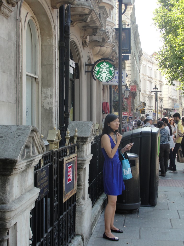girl standing by starbucks holding out phone