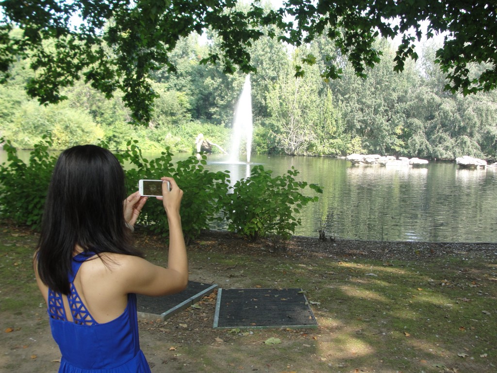 girl using iphone to take picture of lake