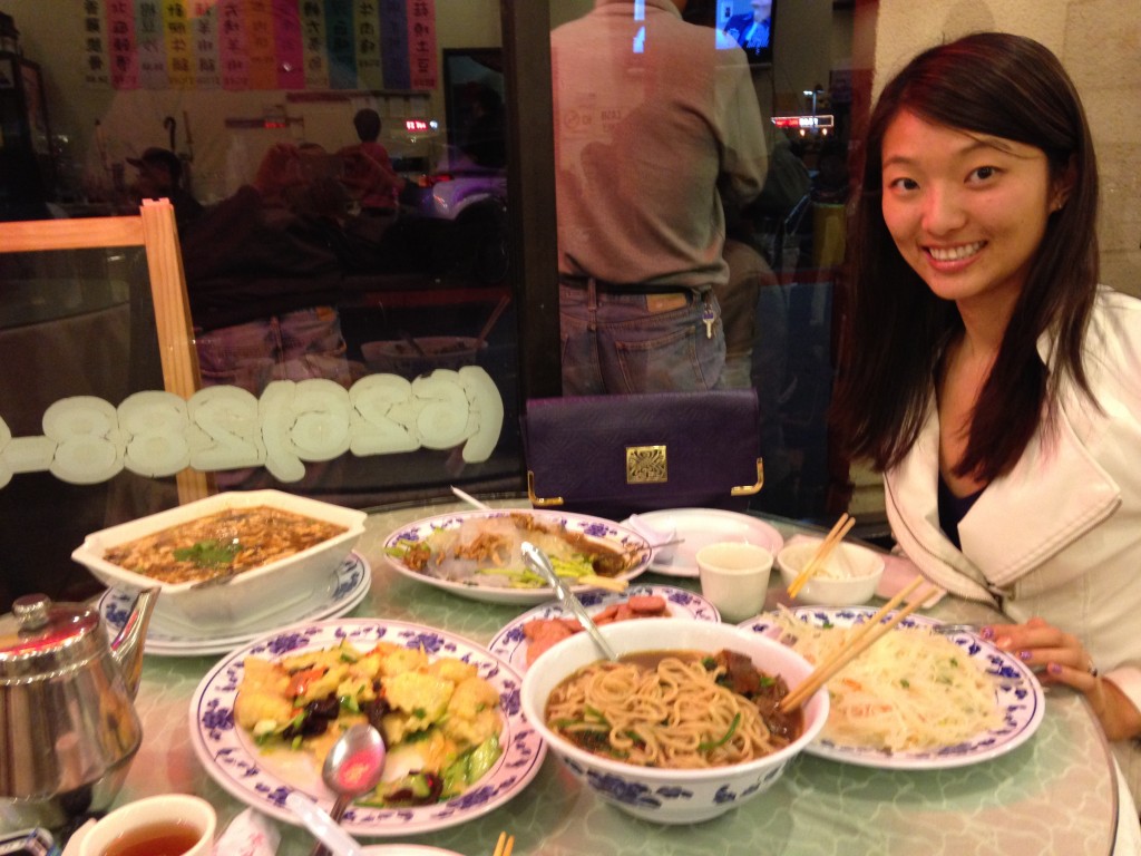 girl sitting at table of chinese restaurant with five massive dishes for just two people