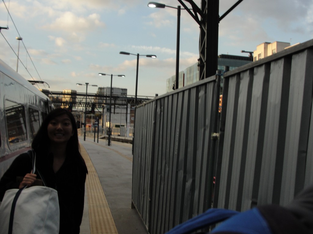 girl grinning with bag near end of train station platform