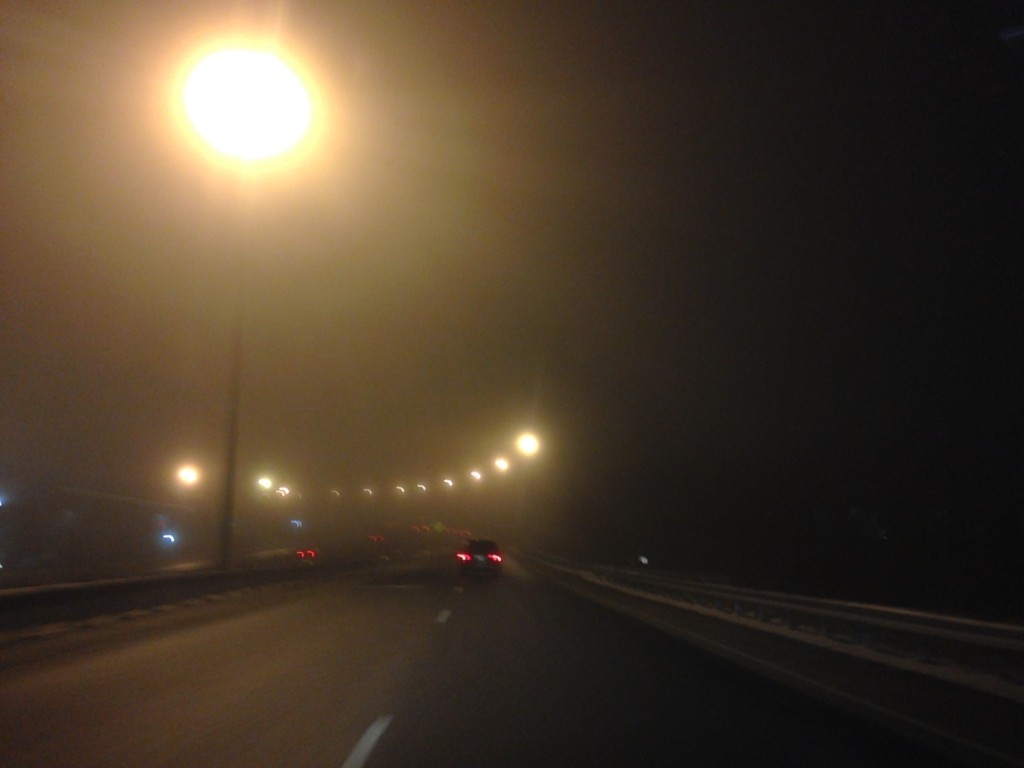 very foggy night with street lights glowing yellow and blurry on the road