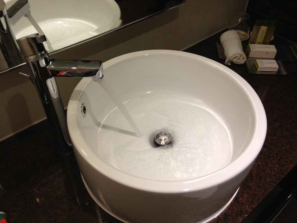 round bowl sink sitting atop bathroom counter with water running