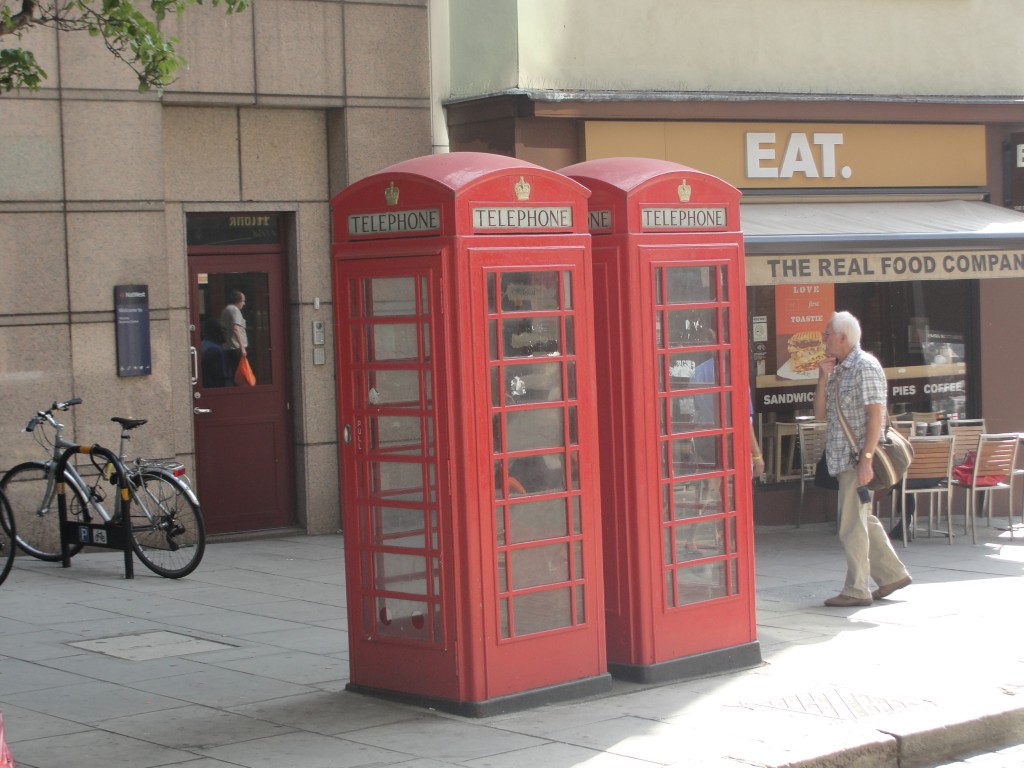 two red british telephone booths on streets of london