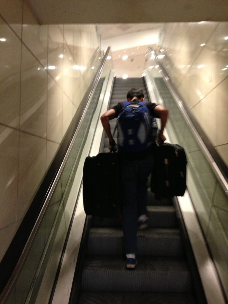 guy carrying two suitcases one in each hand up out of order escalator