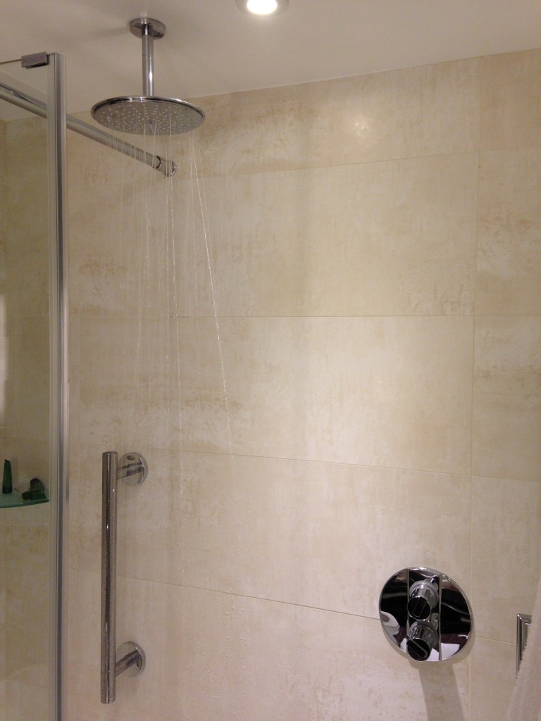 large showerhead extending from ceiling raining down water