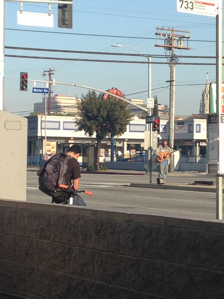 electric guitarist playing music in middle of road at intersection in culver city