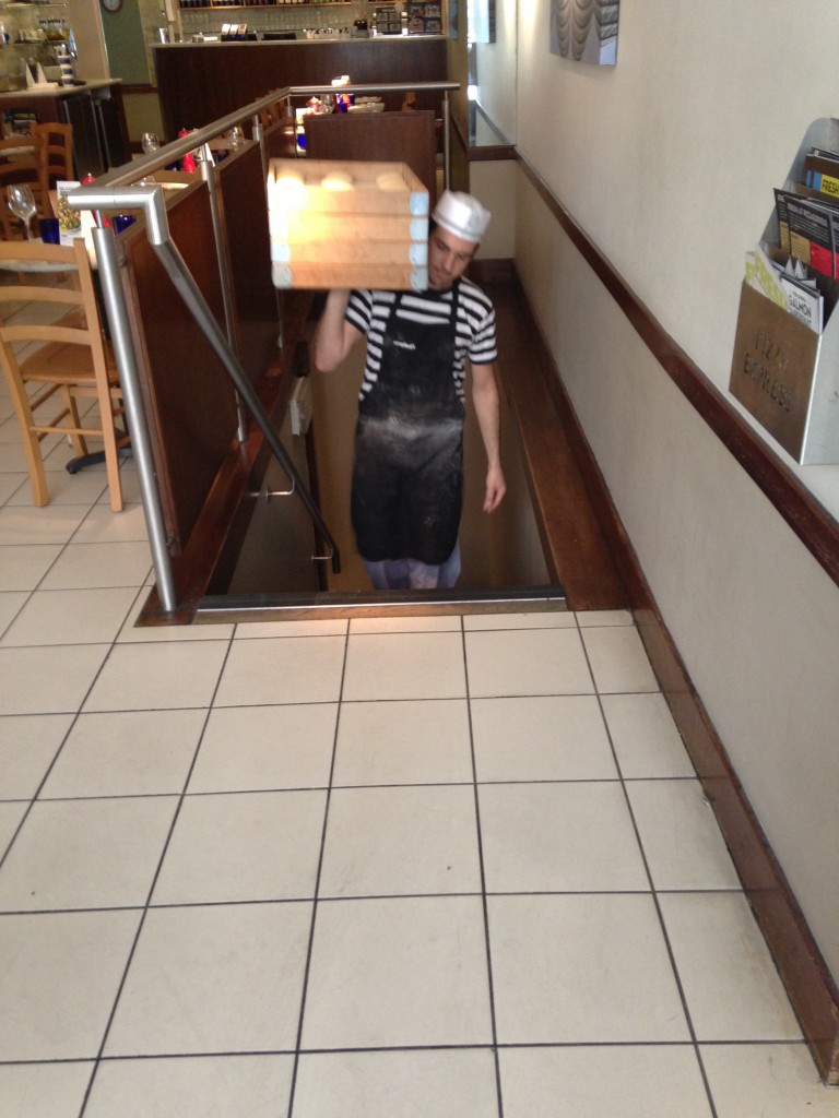 guy walking up stairs holding trays of dough for pizza express pizzas