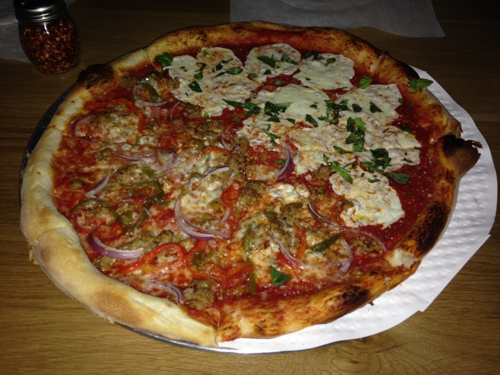 thin crust pizza with half sausage with red onions and half mozzarella with basil