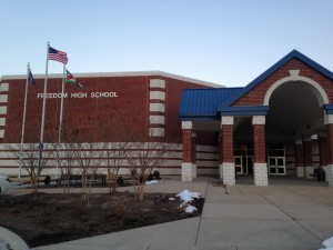 front of freedom high school with entrance, school name, and flags flying