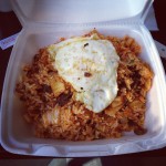 takeout box of kimchi fried rice with fried egg on top