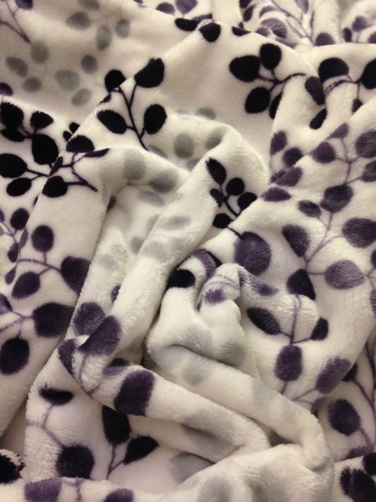 white plush blanket with purple and gray leaf pattern