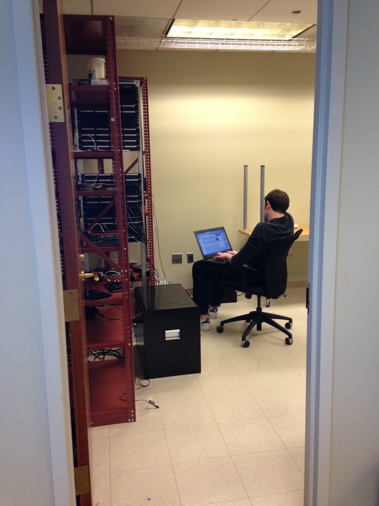 guy sitting in server room working on laptop