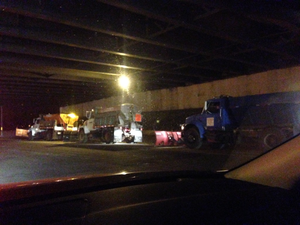 snow plows idling under overpass waiting for snow