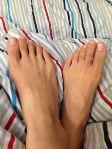 bare feet crossed at ankles sitting atop blanket