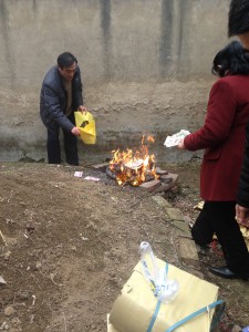 paying respects burning chinese paper money at ancestor's dirt mound grave site