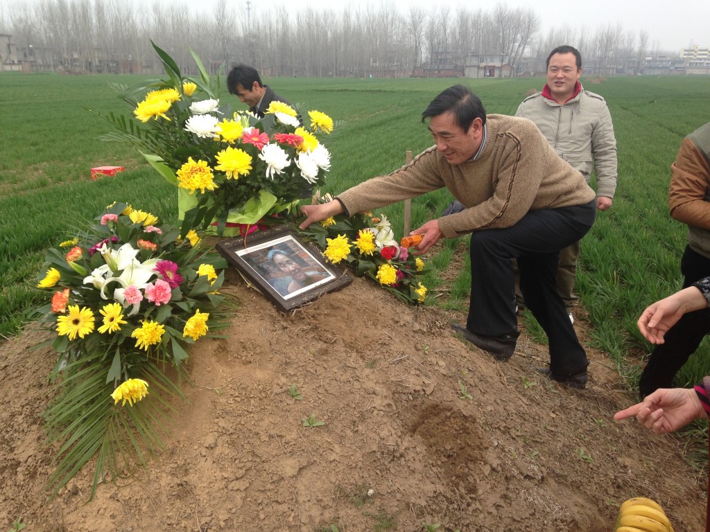 setting up dirt mound grave with flowers, picture, and offerings