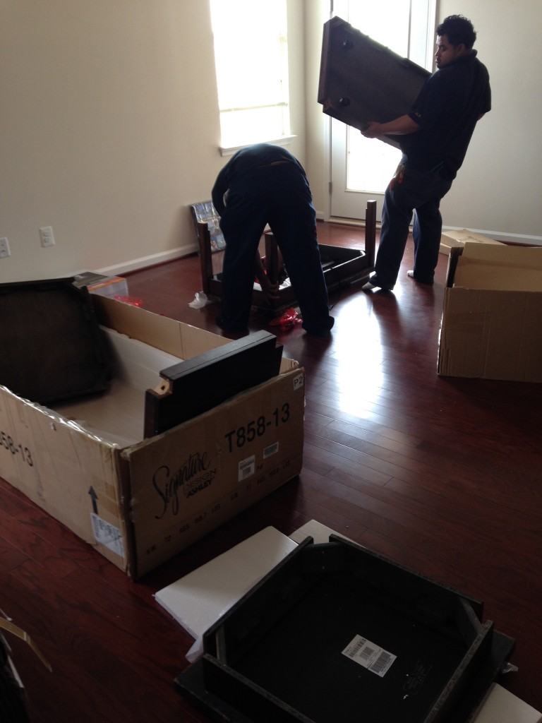 boxes of end tables and coffeetable with two guys assembling the pieces