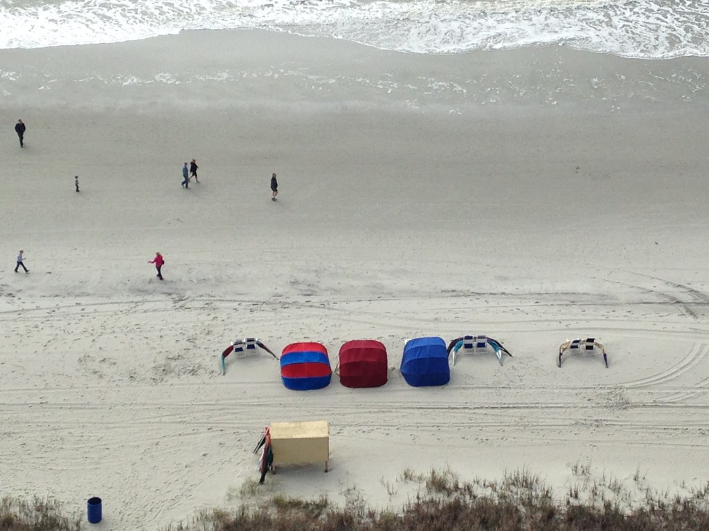 people down on beach and chairs with tents laid out
