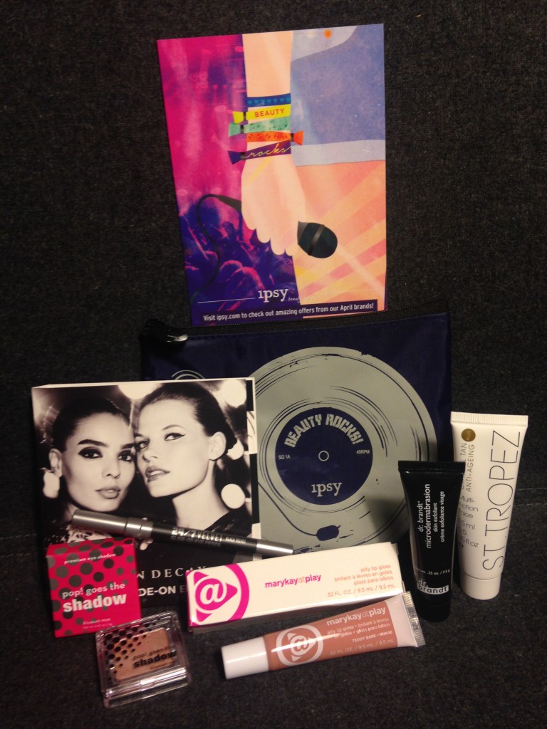 ipsy april 2014 bag items with card including urban decay 24/7 velvet eye pencil, elizabeth mott pop goes the shadow in champagne, mary kay at play jelly lip gloss in teddy bare, dr brandt microdermabrasion, and st tropez gradual tan