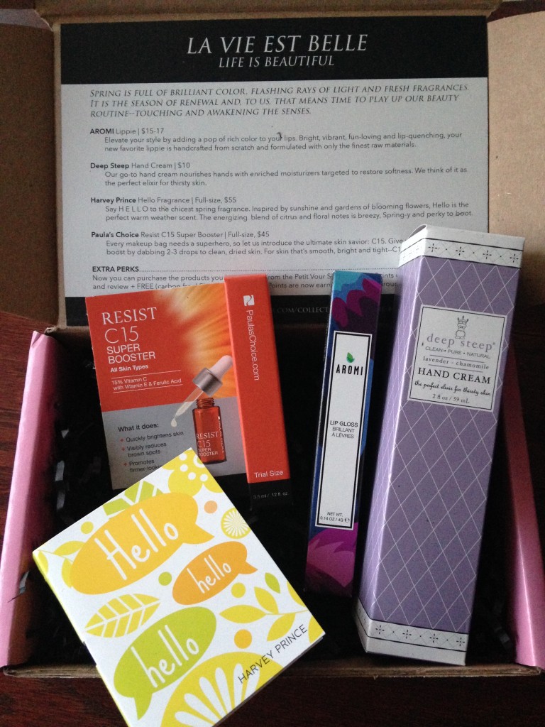 contents of petit vour may 2014 box with harvey prince hello fragrance sample, paula's choice resist c15 super booster, aromi lip gloss in rouge, and deep steep hand cream in lavender chamomile