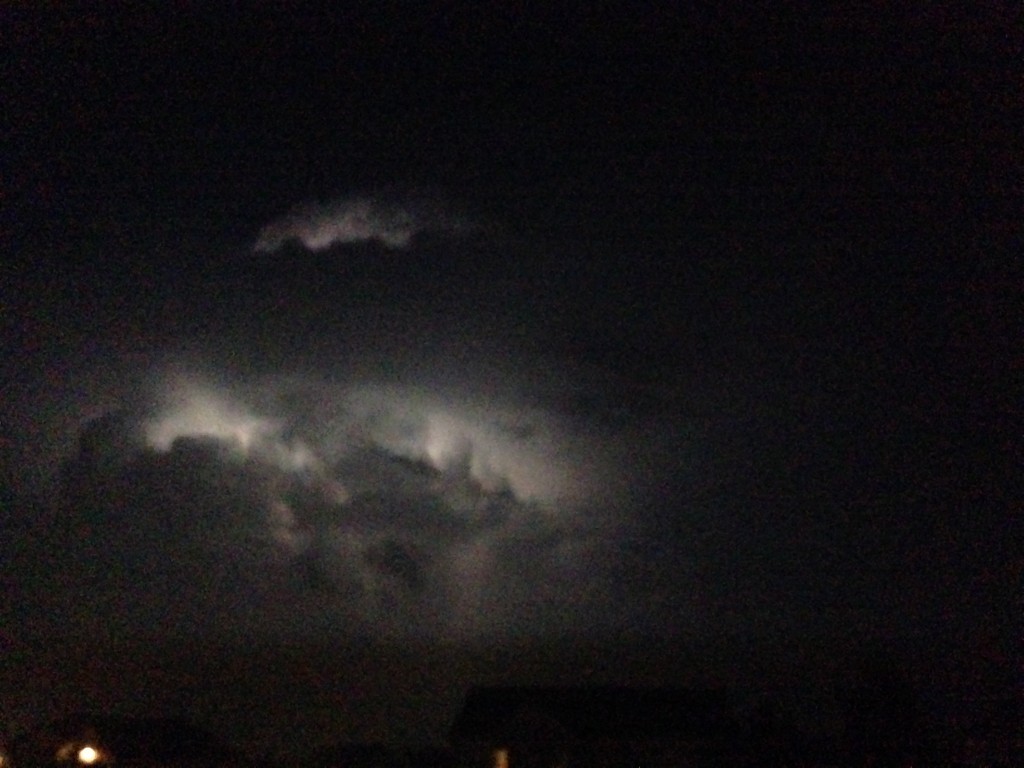 lightning behind cloud at night, lighting up parts of cloud in the darkness