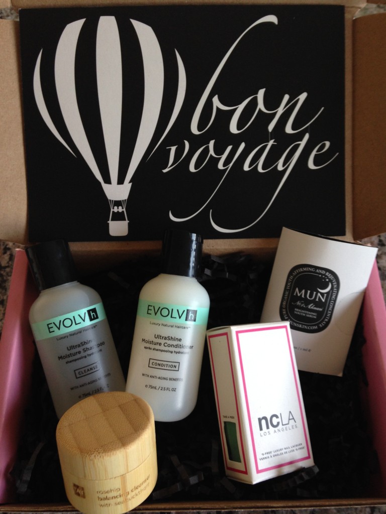 contents of petit vour june 2014 box with evolvh shampoo and conditioner, tay balancing cleanser, mun brightening serum, ncla luxury nail lacquer, and info card with bon voyage theme