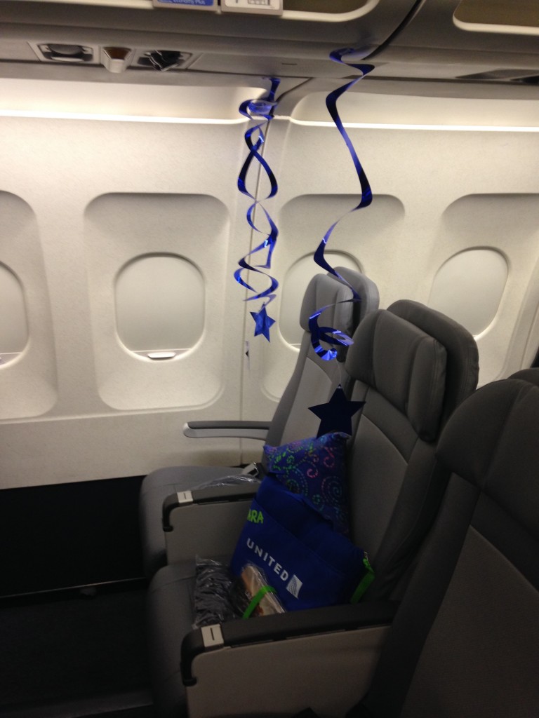 plane seat decorated with blue stars and gifts for make a wish kid heading to los angeles