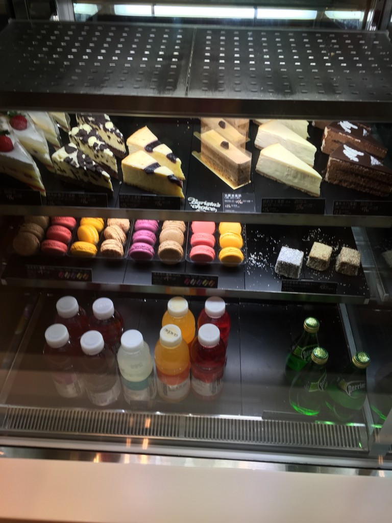 dessert case at mcdonald's mccafe in hong kong with cake slices, macarons, and drinks