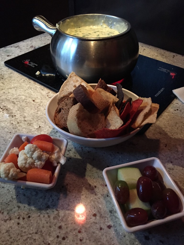 melting pot spinach artichoke cheese fondue with bread, chips, vegetables, and fruits for dipping