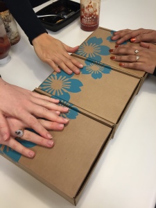 three people's hands each on a different yuzen box lined up