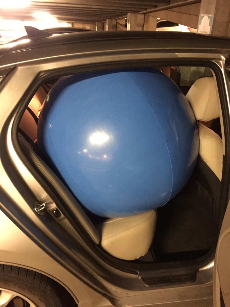 giant blue beach ball squeezed into backseat of car