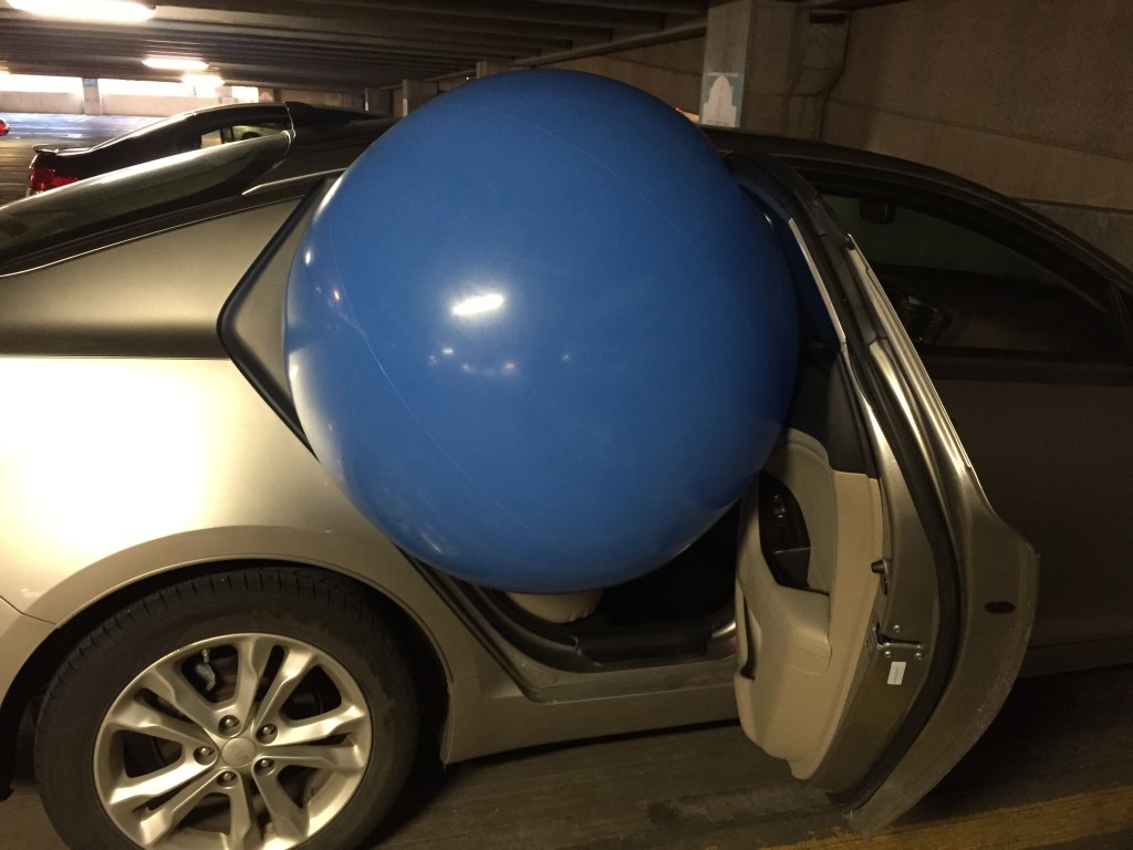 giant blue beach ball being stuffed into backseat of car