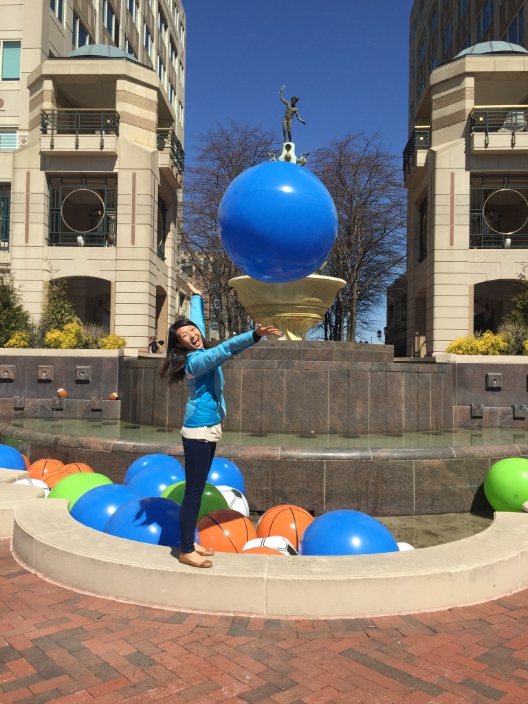 excited girl throwing beach ball in air by fountain filled with balls