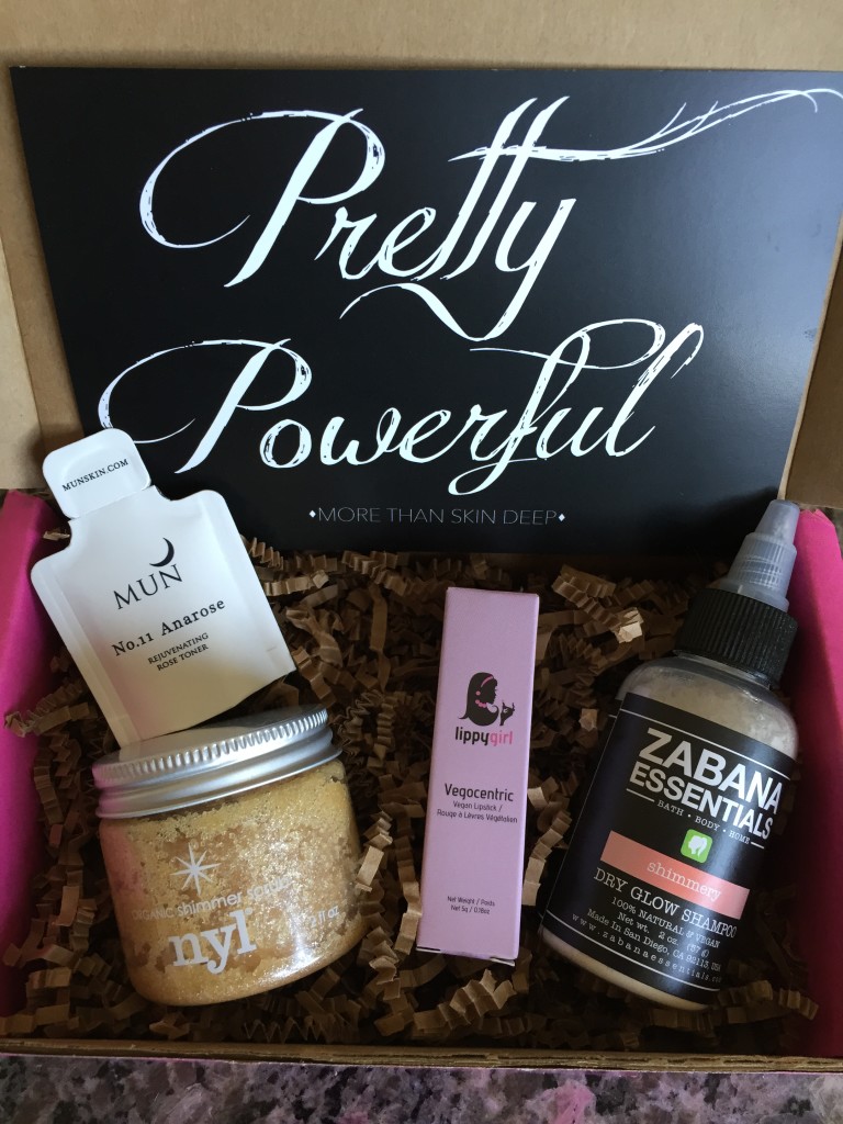contents of petit vour may 2015 box with mun anarose toner, nyl organic shimmer scrub, lippygirl vegan lipstick, zabana essentials dry shampoo, and info card with pretty powerful theme