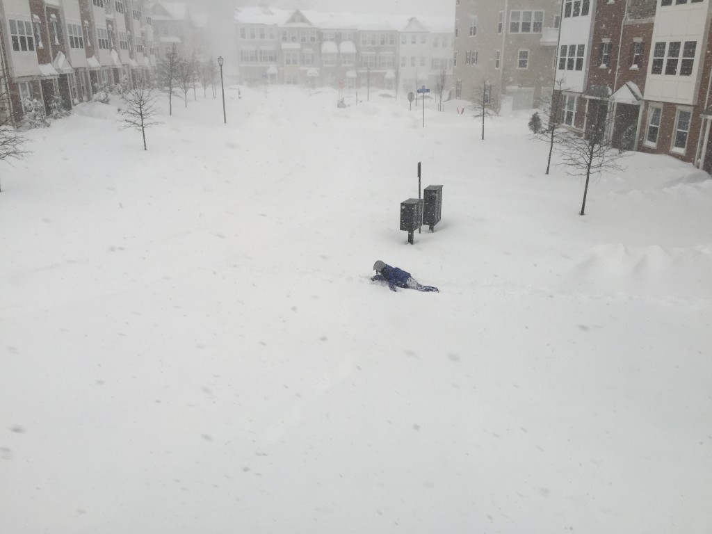 man crawling on belly in deep snow during blizzard 2016